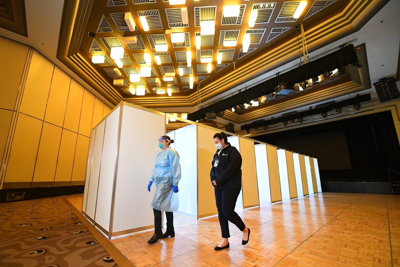 A health care worker and staff member are seen in the Covid-19 staff testing area at the Grand Hyatt Melbourne, one of three major hotels refitted to make them appropriate to house Australian Open tennis players. Image: AAP Image/James Ross.