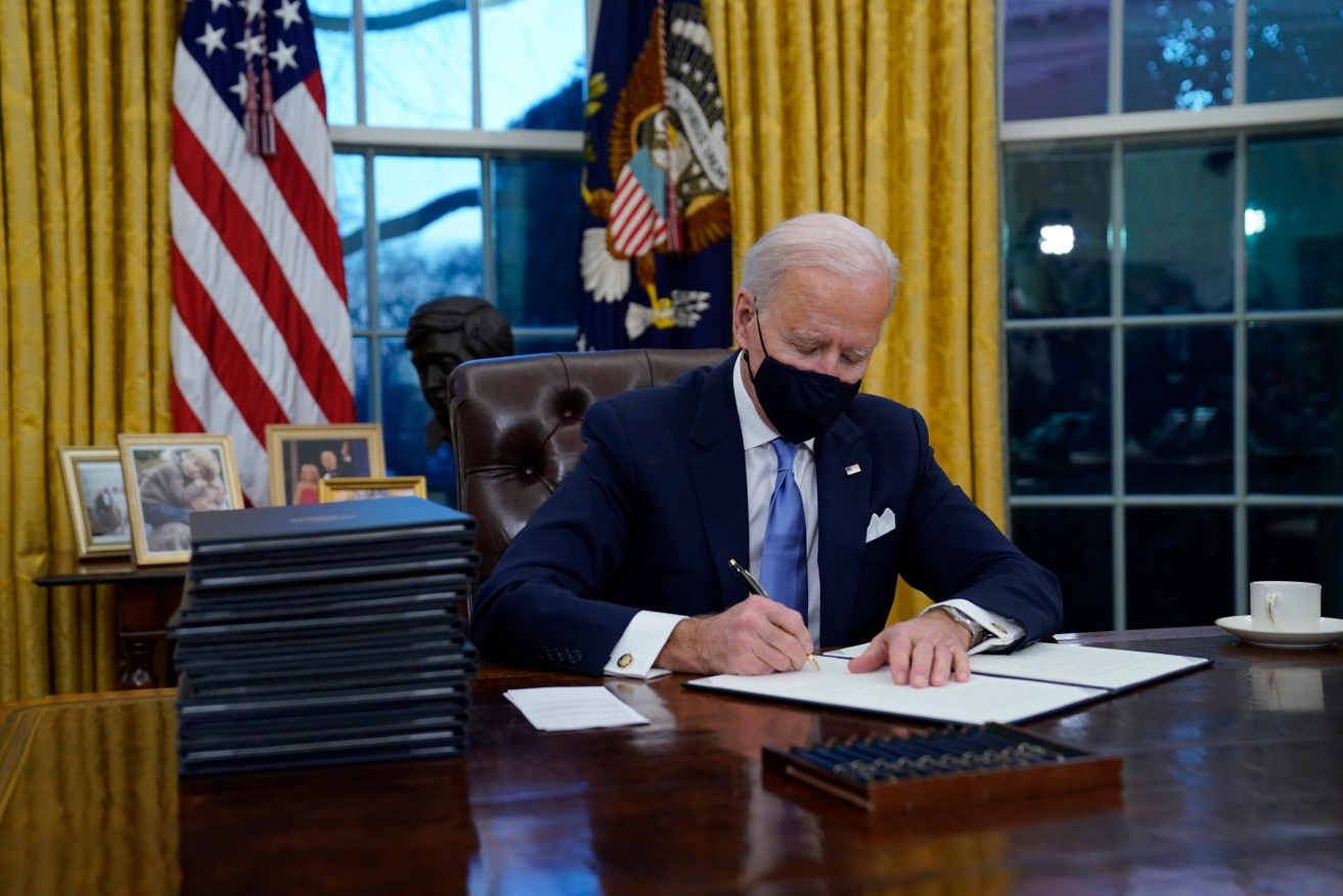 President Joe Biden signs his first of 17 executive orders in the Oval Office of the White House today (AP Photo/Evan Vucci)