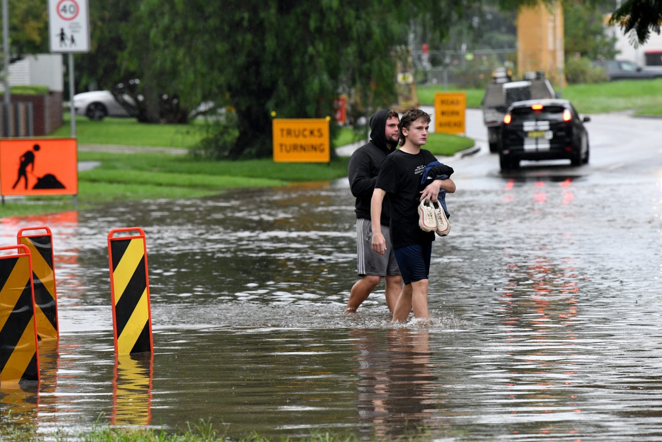 People walk through floodwater as it submerges the road on the corner of Ladbury Ave and Memorial Ave, Penrith, NSW (AAP Image/Bianca De Marchi) 
