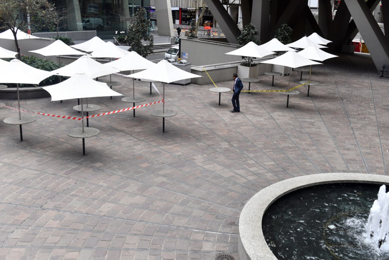 An office worker walks in a deserted food square in the central business district in Sydney (AAP Image/Mick Tsikas)