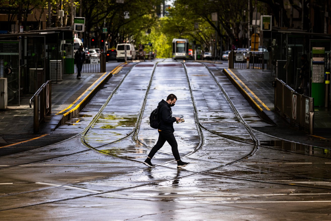 A lone person is seen crossing Collins Street in Melbourne, Monday, October 4, 2021 (AAP Image/Daniel Pockett).