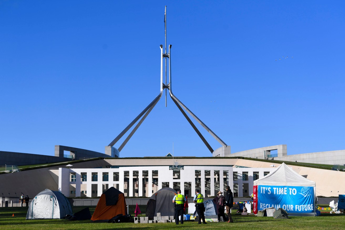Extinction Rebellion protesters set up tents as part of a protest outside Parliament House in Canberra, Monday, October 25, 2021. (AAP Image/Lukas Coch)