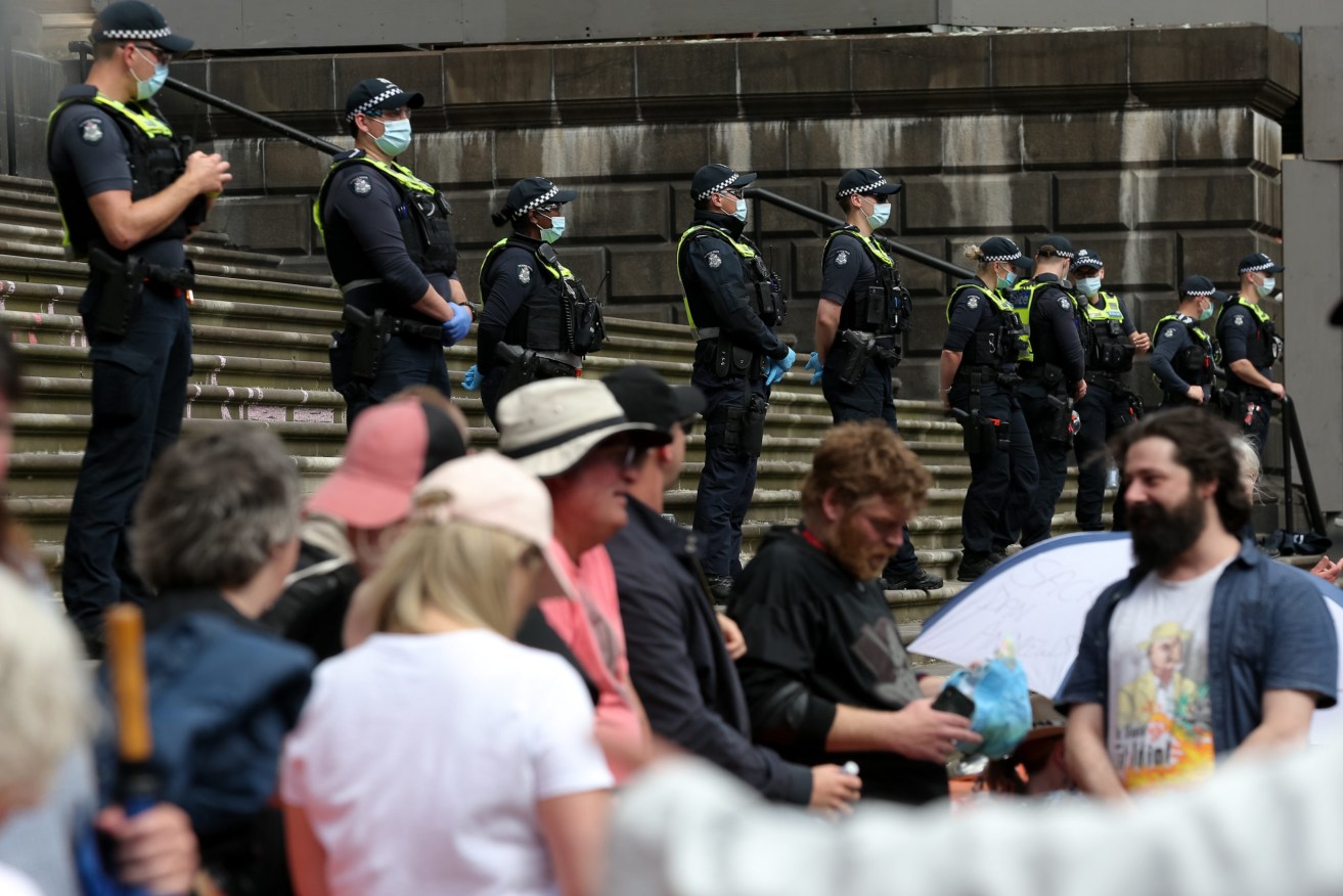 Police at Victoria's parliament house watch over a protest against the government's pandemic bill. Photo: AAP/Con Chronis