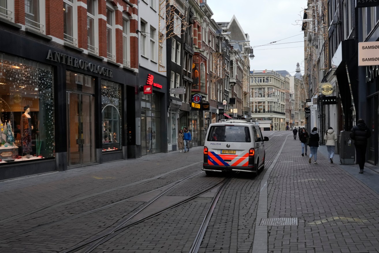 Police patrol an near-empty street in the centre of Amsterdam. All non-essential stores are closed until mid-January. Photo: AP/Peter Dejong