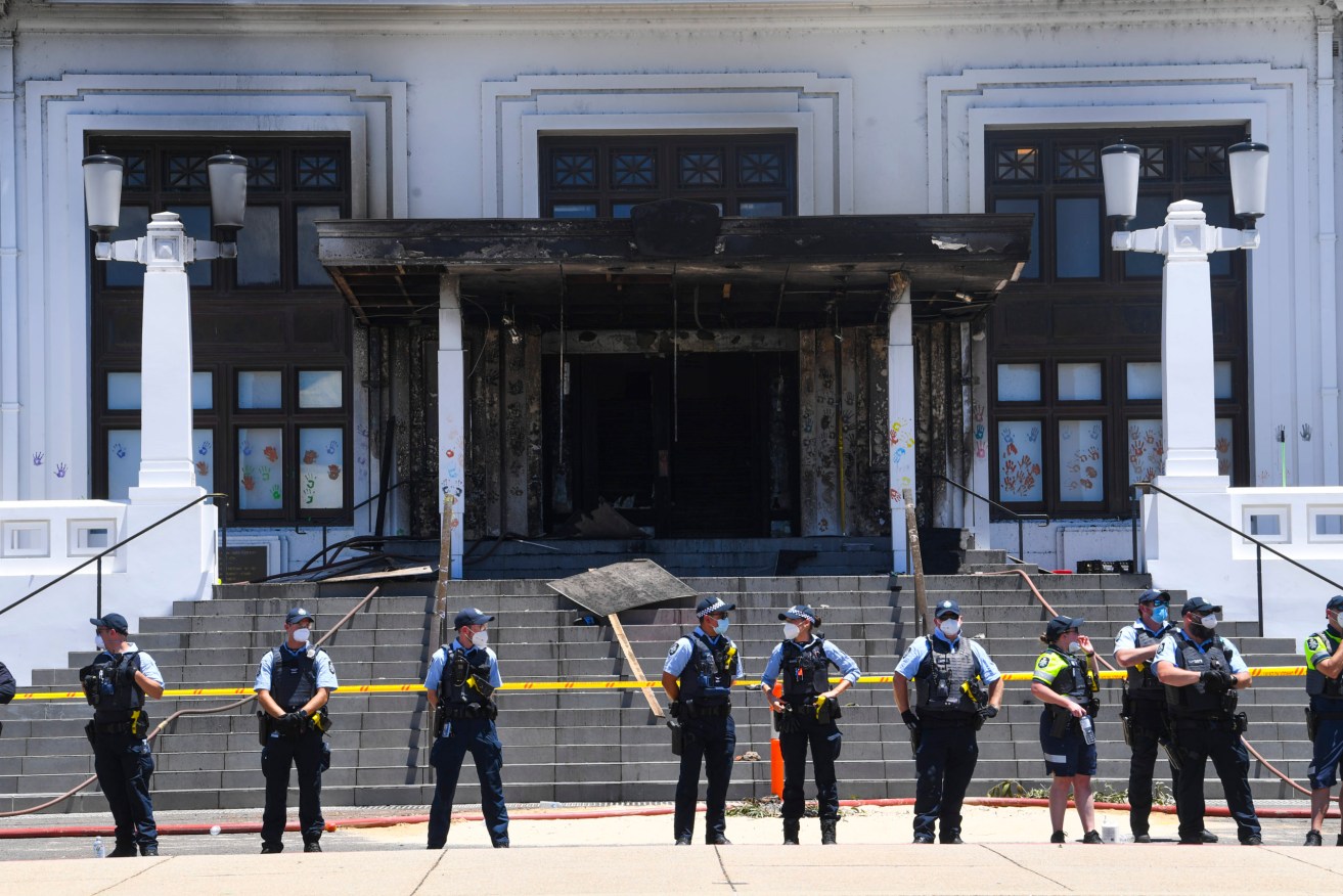 Police officers stand guard outside the fire damaged entrance to Old Parliament House in Canberra, Thursday, December 30, 2021. (AAP Image/Lukas Coch) 