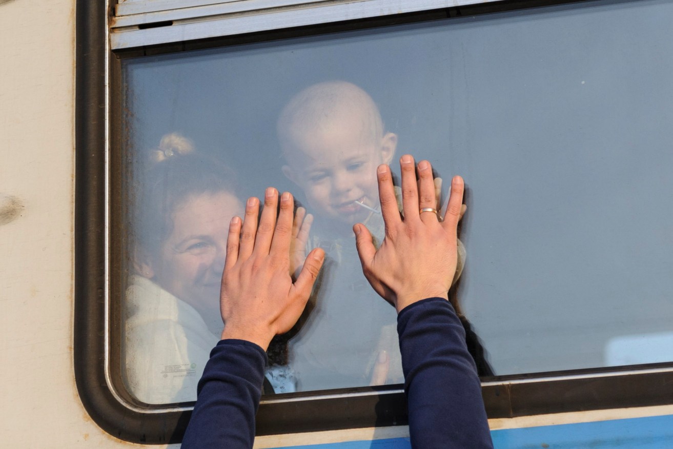 A mother and child leave the railway station in Lviv for Poland as Russian forces approach. Photo: EPA/MYKOLA TYS