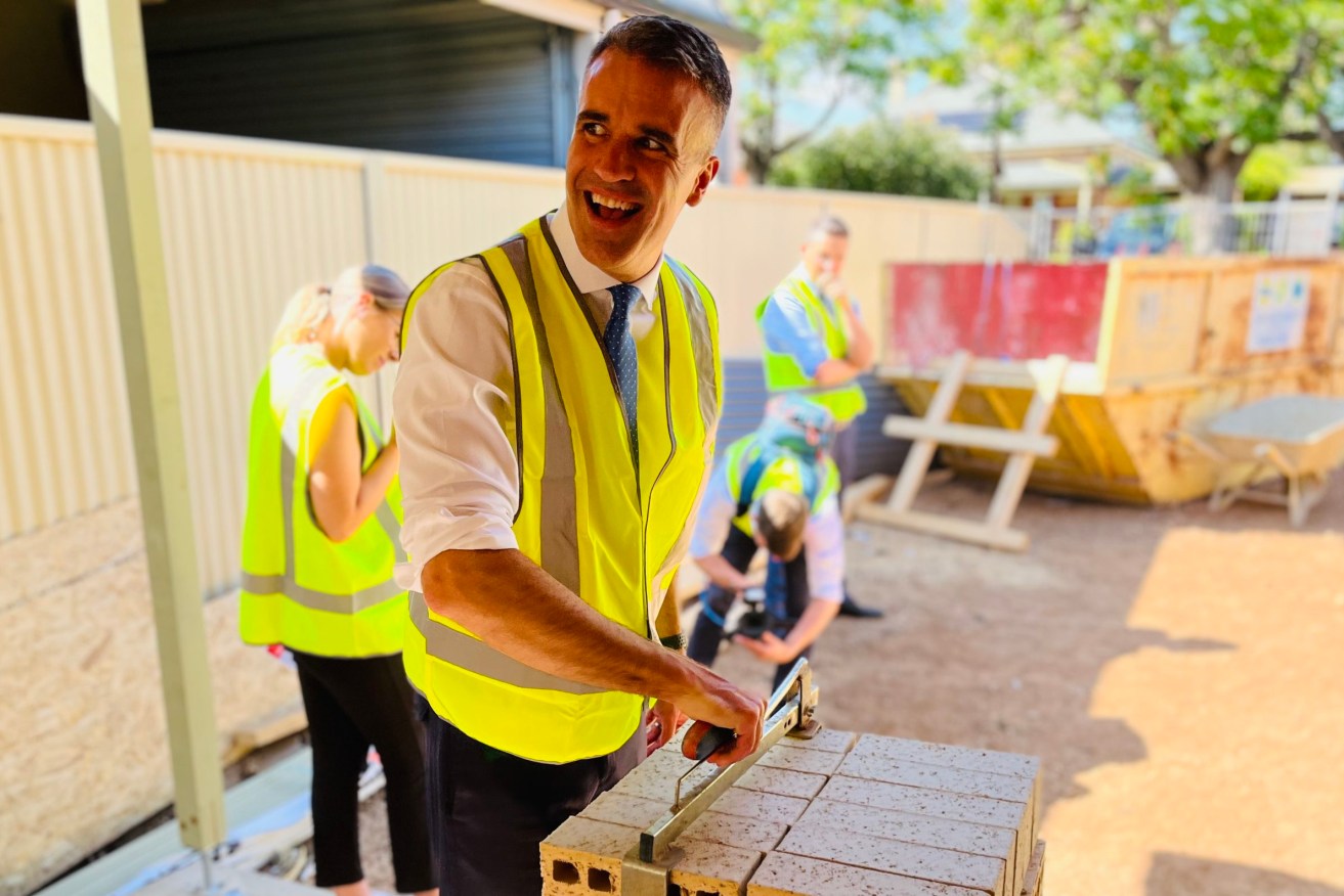 Peter Malinauskas tries his hand at brick-carting on the campaign trail today. Photo: Tom Richardson / InDaily