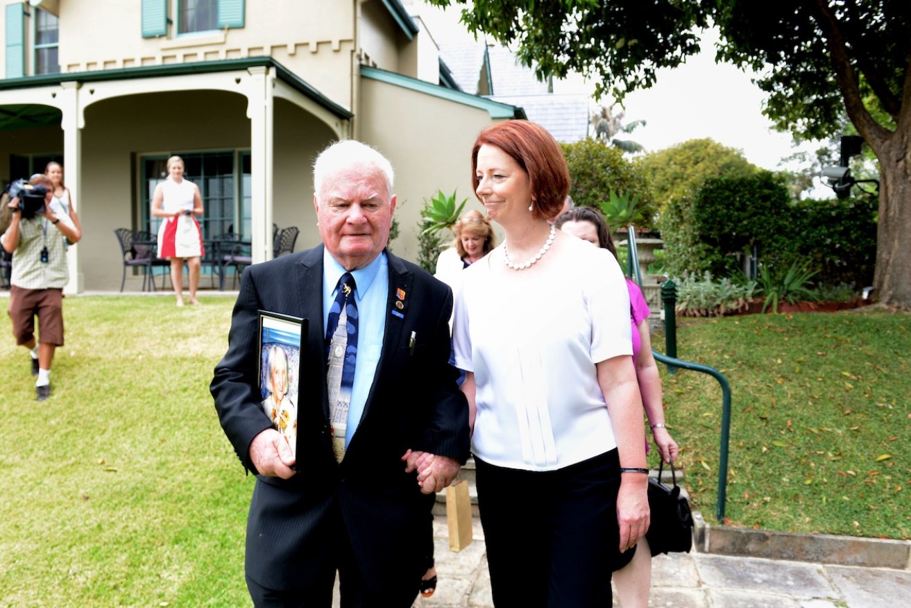 Then Prime Minister Julia Gillard holds the hand of John Hennessey during an official reception at Kirribilli House in Sydney in 2013. Photo: Tracey Nearmy / AAP