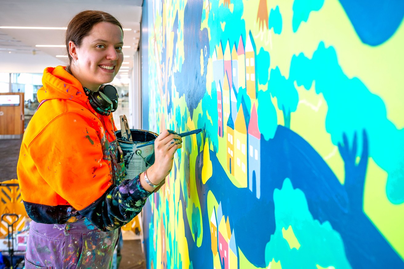 Lucinda Penn works on her National Park City mural at Adelaide Airport.