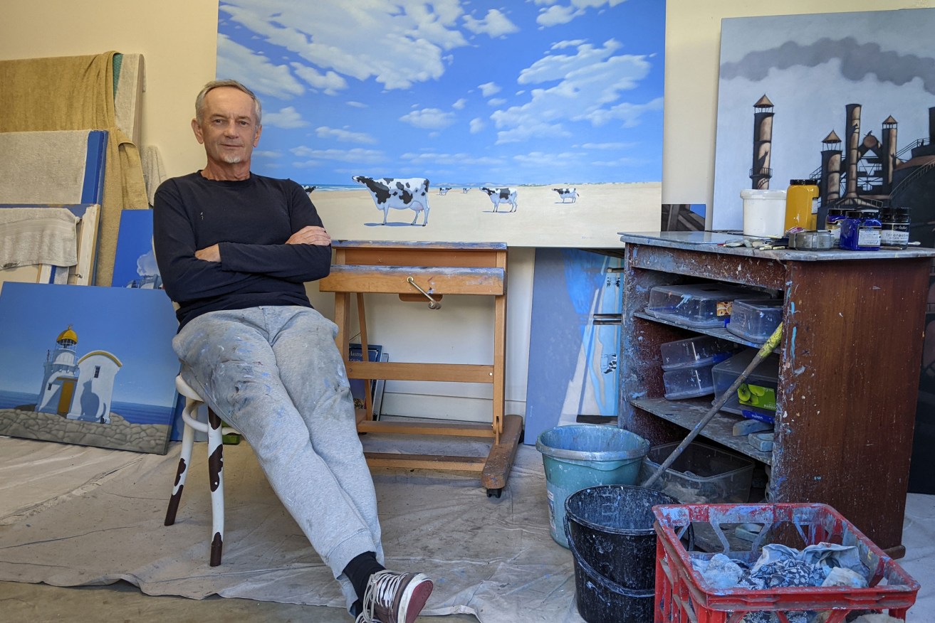 Andrew Baines in his Grange studio, with one of his famous paintings of cows on the beach sitting on the easel behind him. Photo: Carolyn Wade