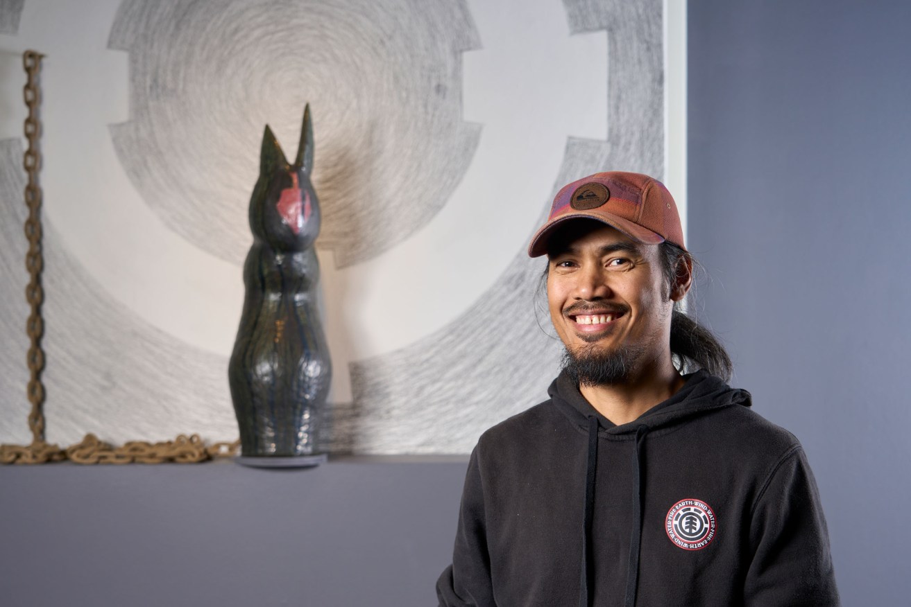 Mark Valenzuela with works in his 2022 SALA exhibition at Adelaide Central Gallery. Photo: Sam Roberts