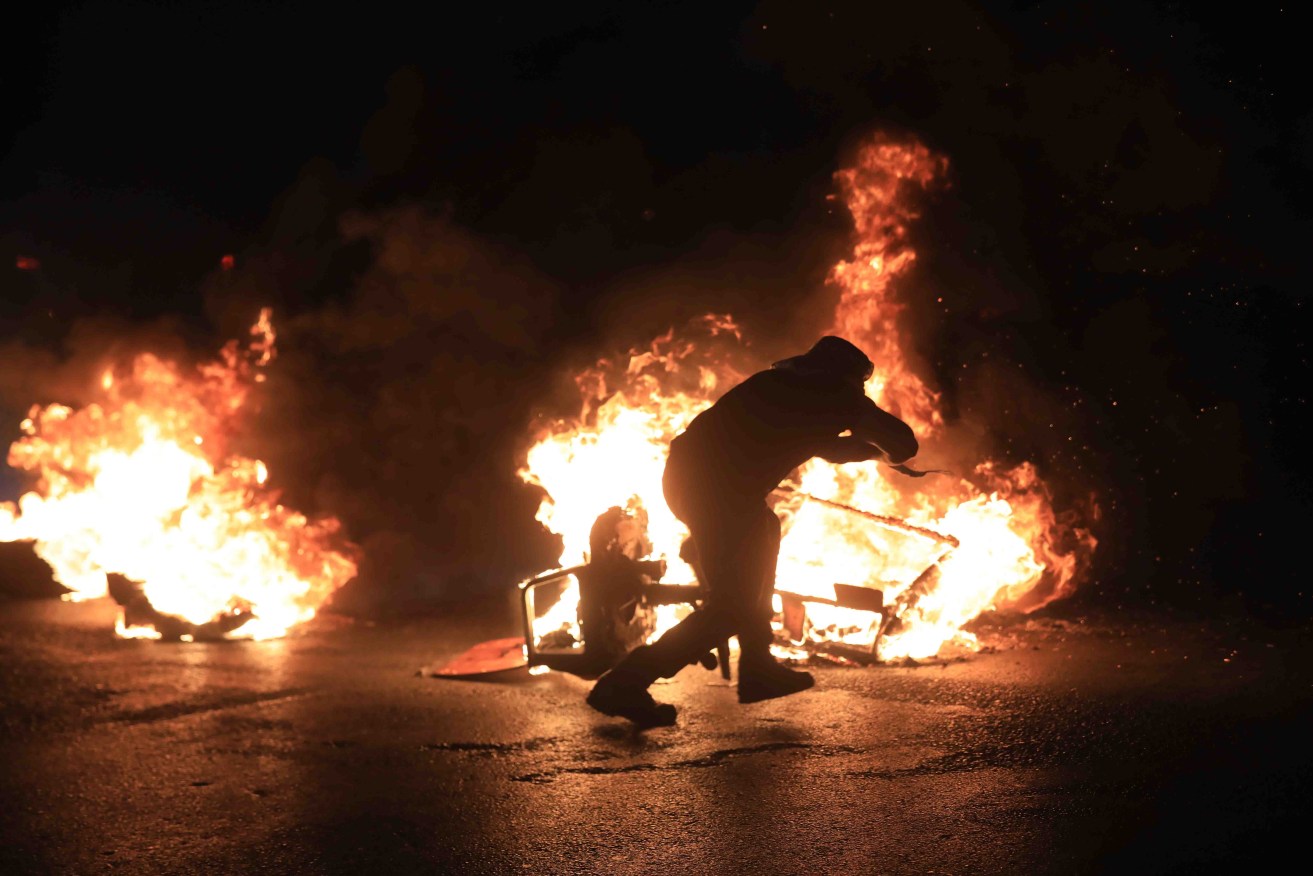 A Palestinian demonstrator burns tires to block a street near the Huwwara checkpoint, south of the West Bank city of Nablus. Photo:  EPA/Alaa Badarneh