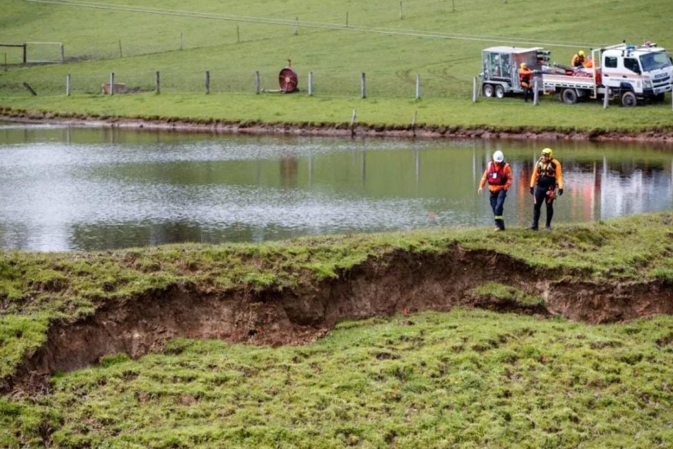 Emergency workers inspect a collapsing wall which threatened to release water from a private dam into Echunga. Photo: AAP/Matt Turner