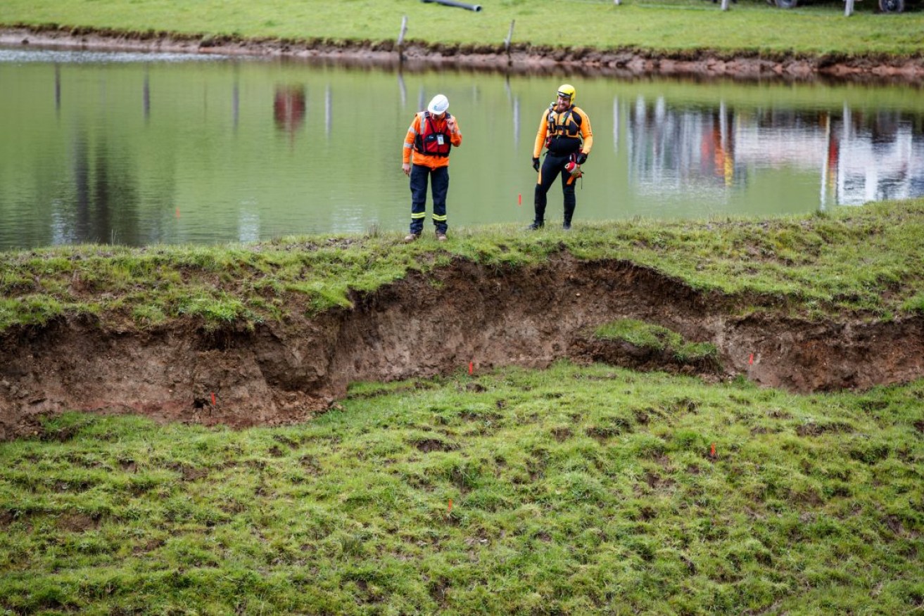 Emergency workers inspect a collapsed part of a farm dam wall at Echunga on Wednesday. Photo: AAP/Matt Turner