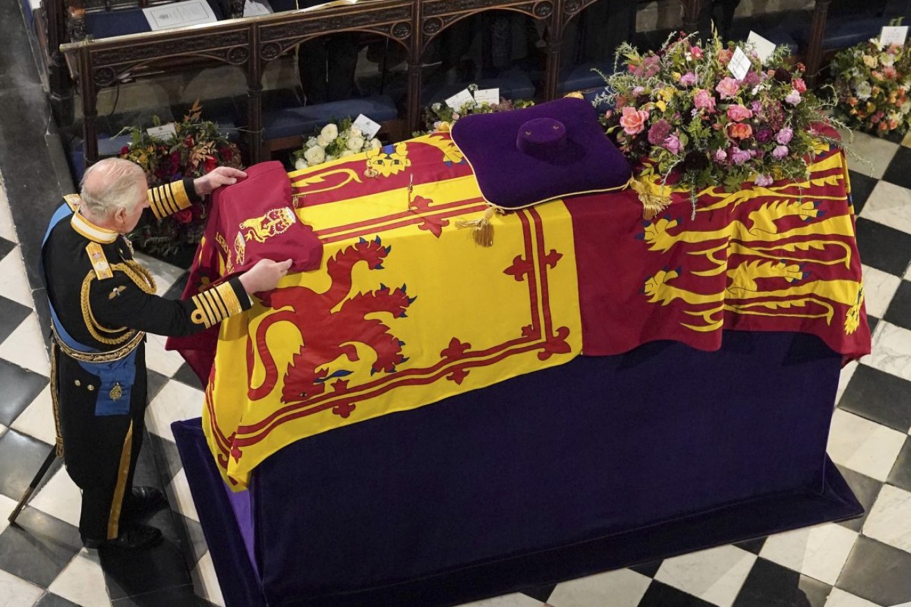 King Charles III places the Queen's Company Camp Colour of the Grenadier Guards on the coffin at the Committal Service for Queen Elizabeth II, held at St George's Chapel in Windsor Castle. Photo: AP/Jonathan Brady.