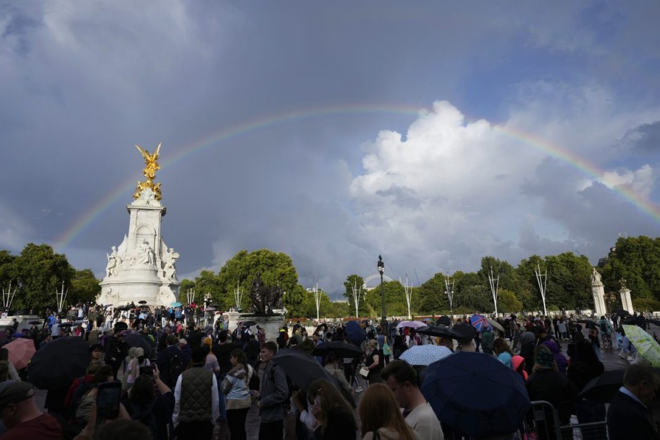 People gather outside Buckingham Palace in London as a double rainbow appears before well-wishers fell into silence as the palace lowered its flag. Photo: AP/Frank Augstein