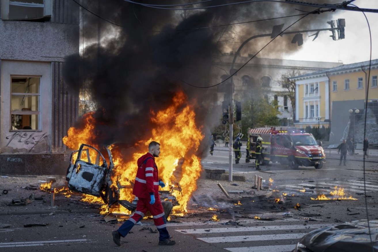 A medical worker runs past a burning car after a Russian attack in Kyiv. Photo: AP/Roman Hrytsyna