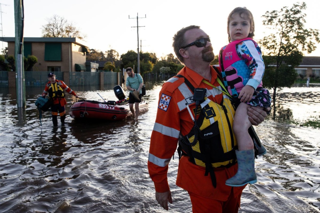 SES personnel help a family leaving their home in Shepparton, Victoria, on Sunday. Photo: AAP/Diego Fedele.
