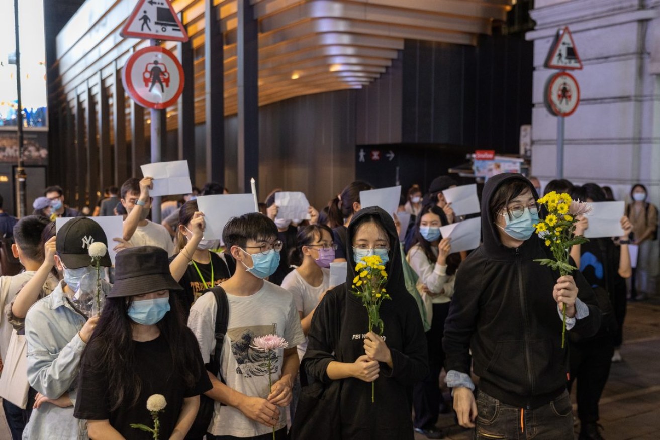 Mourners hold flowers during a vigil for the victims of China’s zero-COVID policy and the victims of the Urumqi fire in Hong Kong. Photo: EPA/Jerome Favre