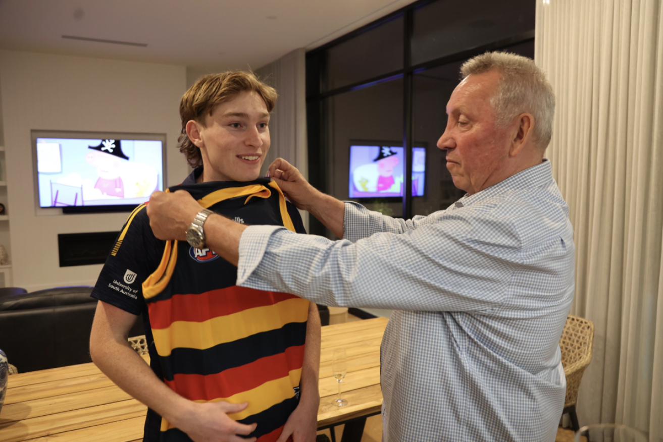 Jim Michalanney measures up son Max for a Crows guernsey. Photo: Adelaide Football Club/Twitter