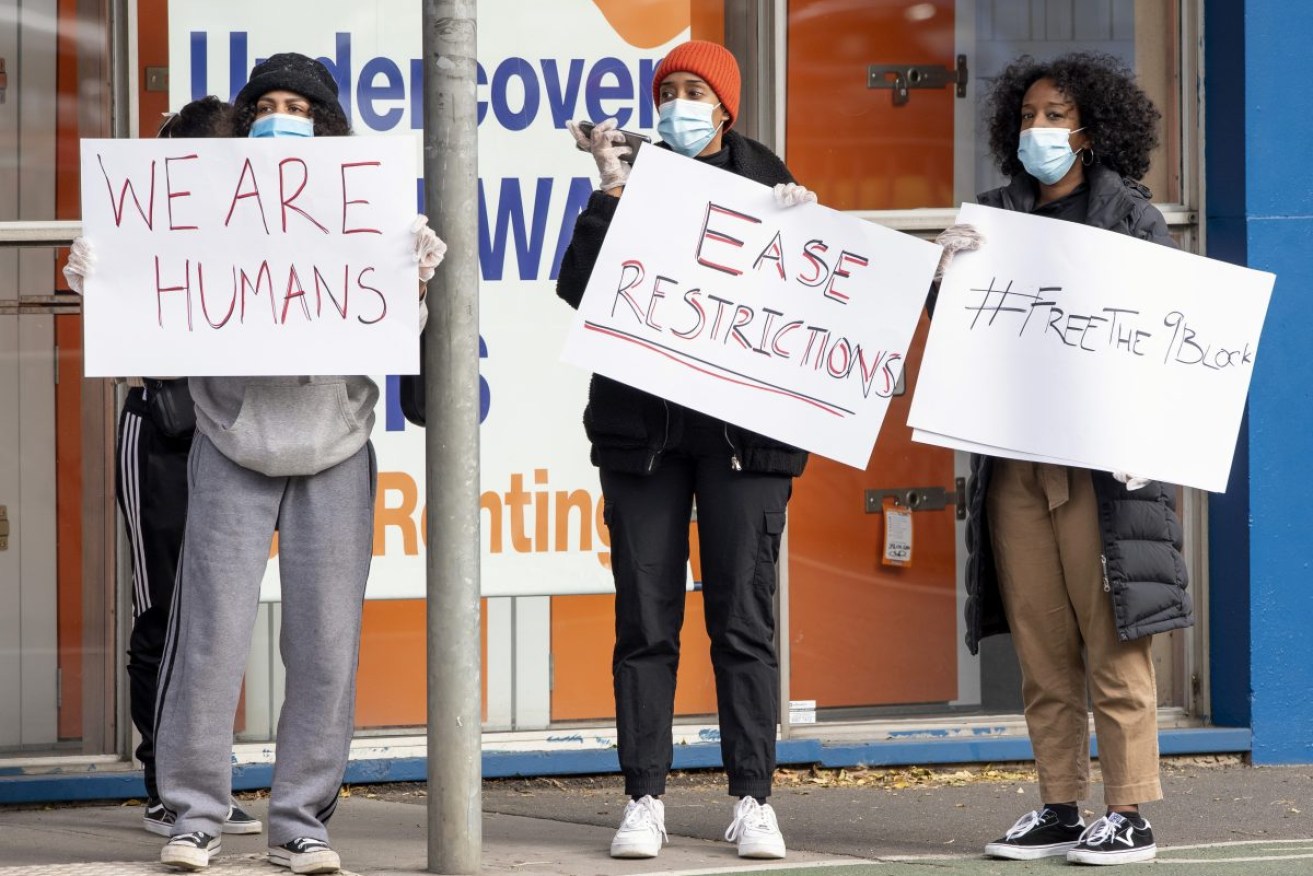 Women hold signs outside housing commission apartments during one of Melbourne's lockdown in 2020. Photo: AP/Andy Brownbill