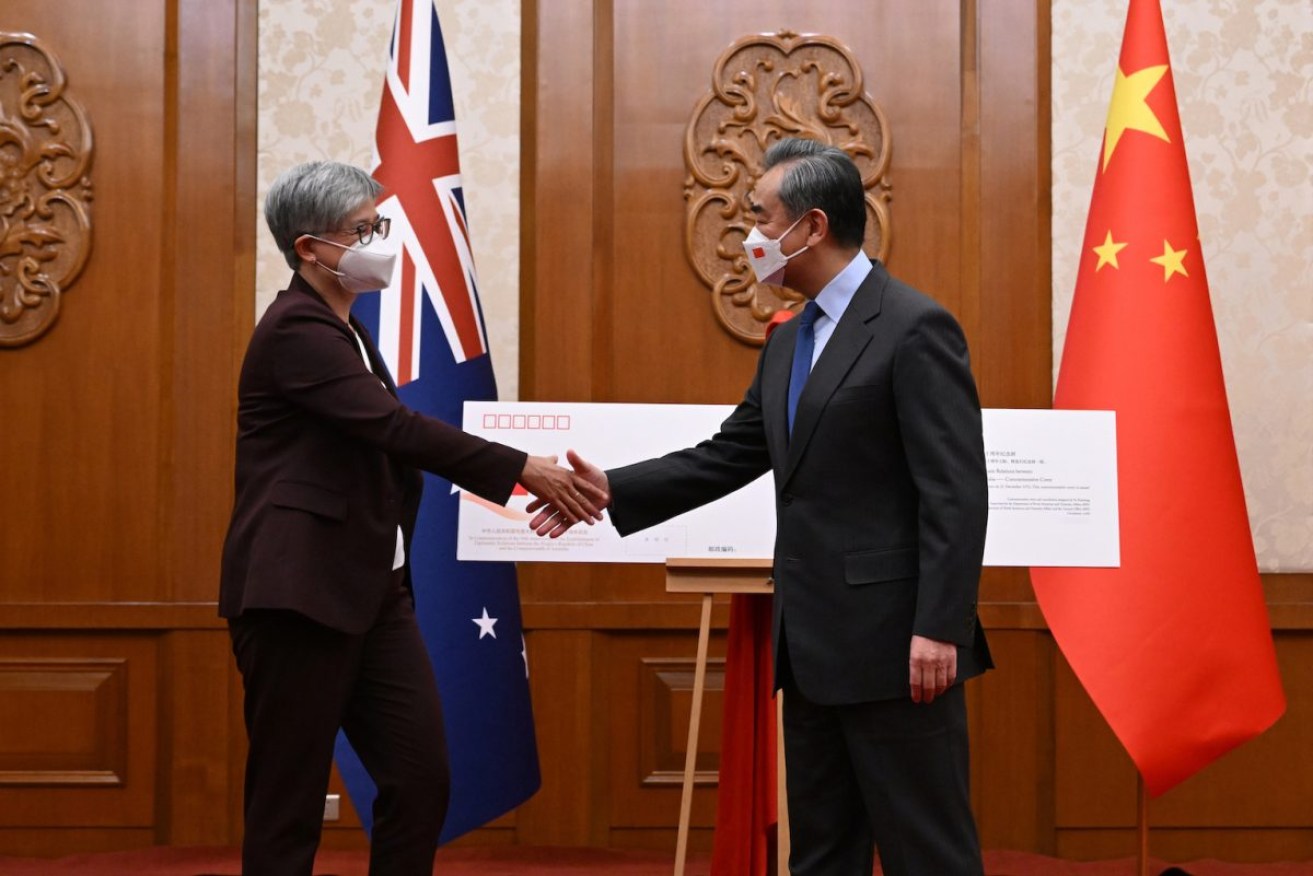 Australian Foreign Minister Penny Wong and Chinese Foreign Minister Wang Yi unveil a commemorative envelope during a ceremony on the 50th anniversary of the establishment of diplomatic relations between Australia and China. Photo: AAP/Lukas Coch