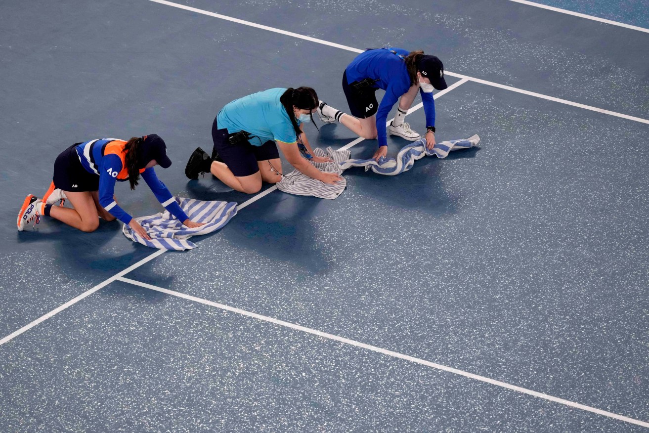 Tennis cinderellas? Ball kids dry the court after rain at the 2022 Australian Open. Photo: AP/Simon Baker