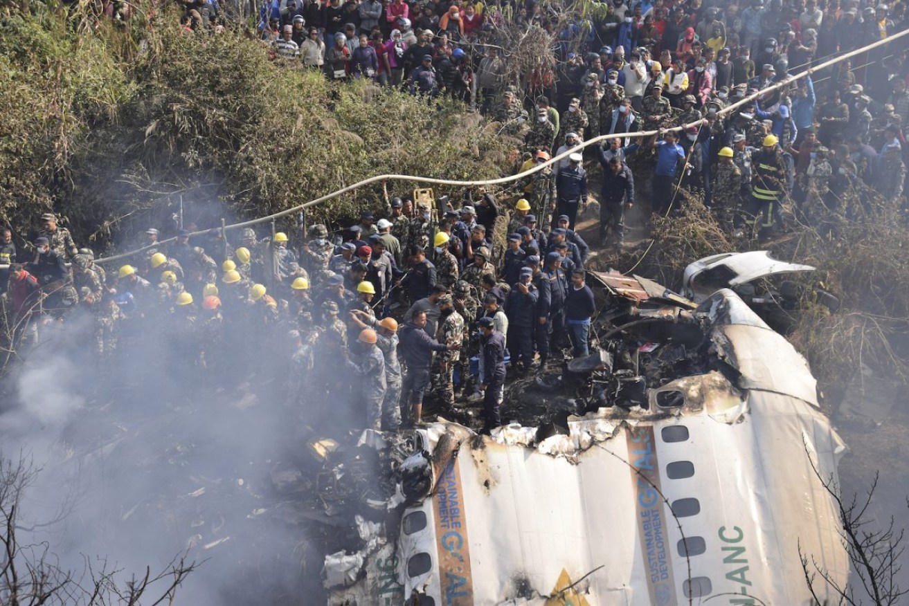 Nepalese rescue workers and civilians gather around the wreckage of the passenger plane that crashed in Pokhara, Nepal. Photo: AP/Krishna Mani Baral