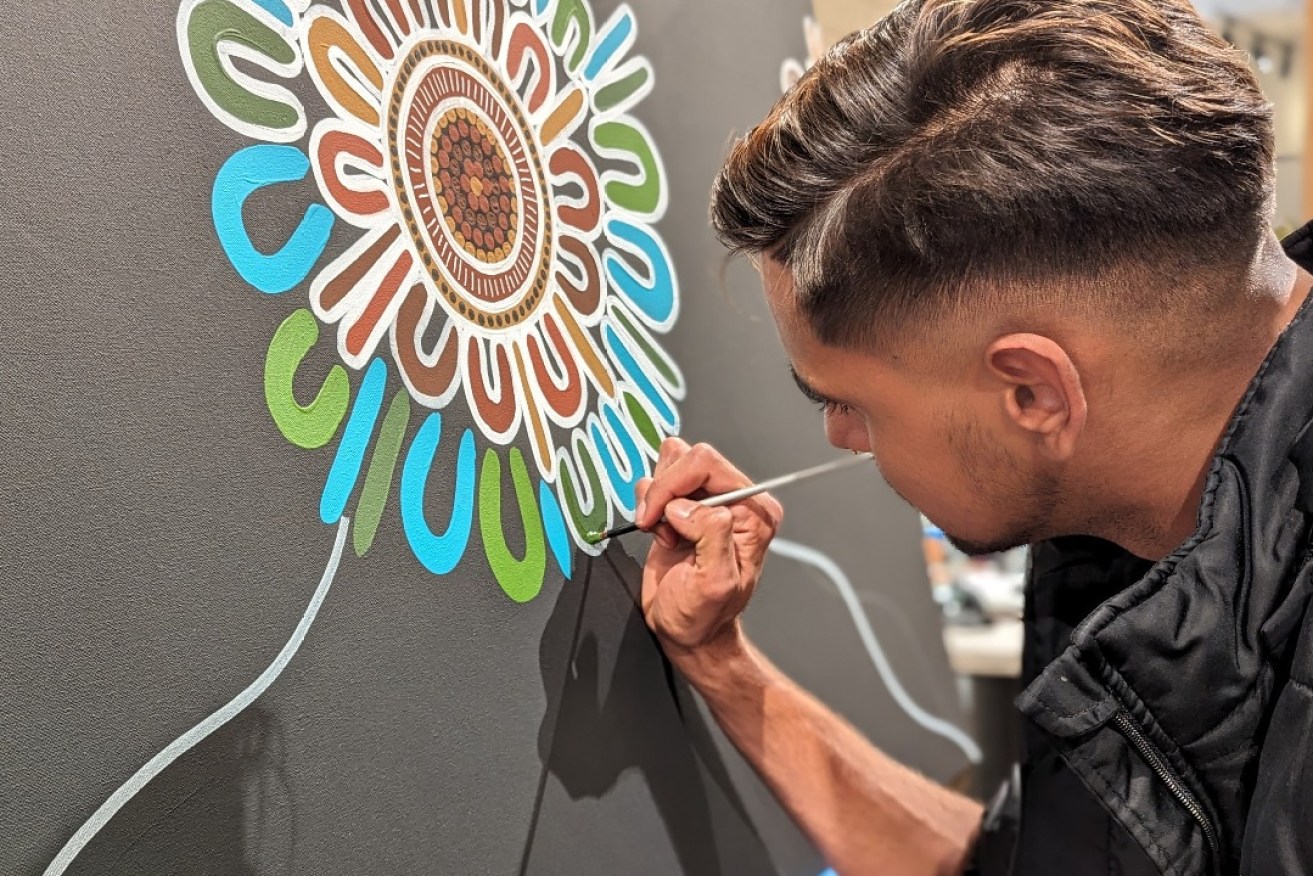 Artist Presten Warren, winner of the BHP Carrapateena PPE art competition, undertaking a live painting at BHP Olympic Dam, Roxby Downs, on Sunday. 