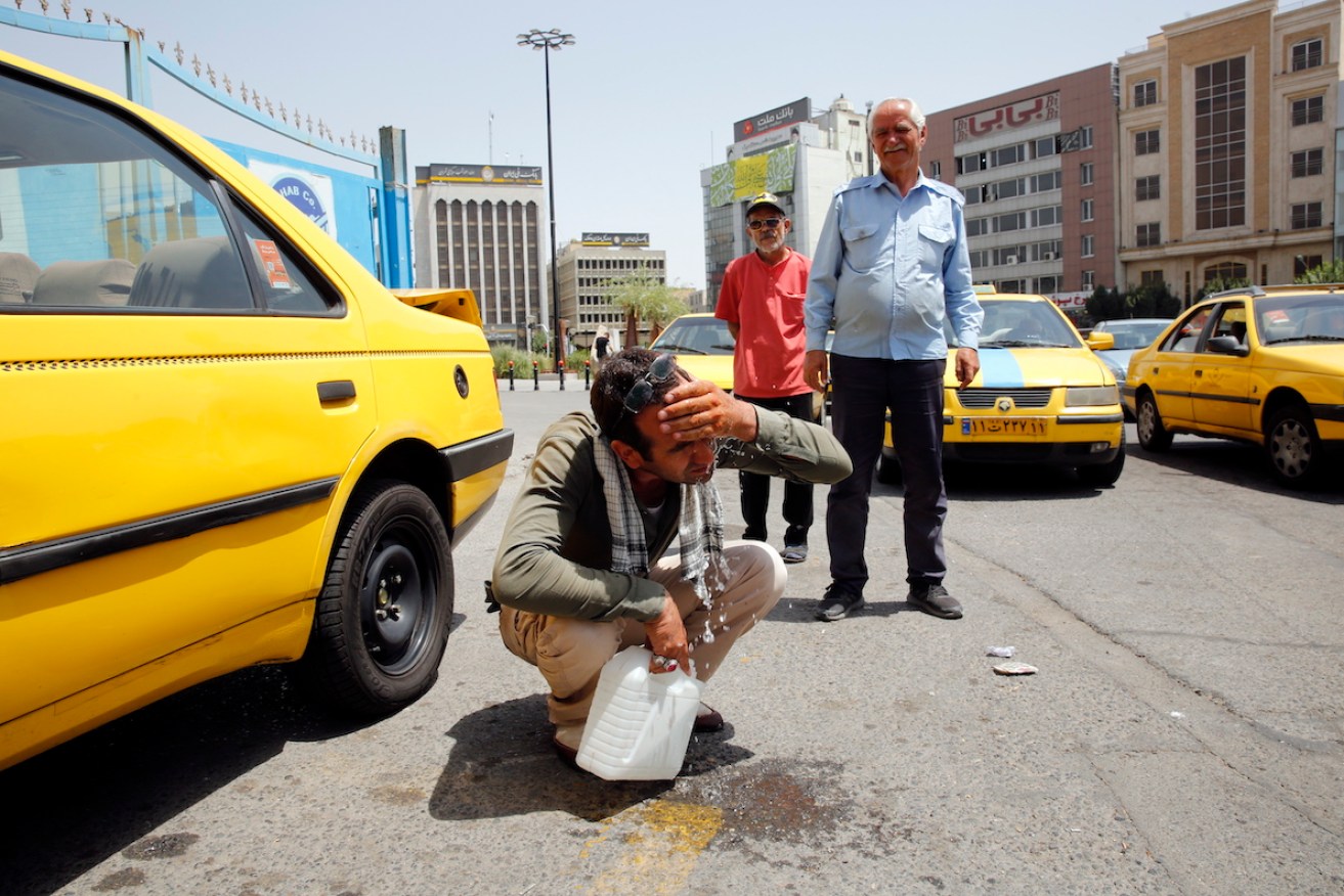 A taxi driver tries to cool down in Tehran. Photo: EPA/ABEDIN ATEHRKENAREH