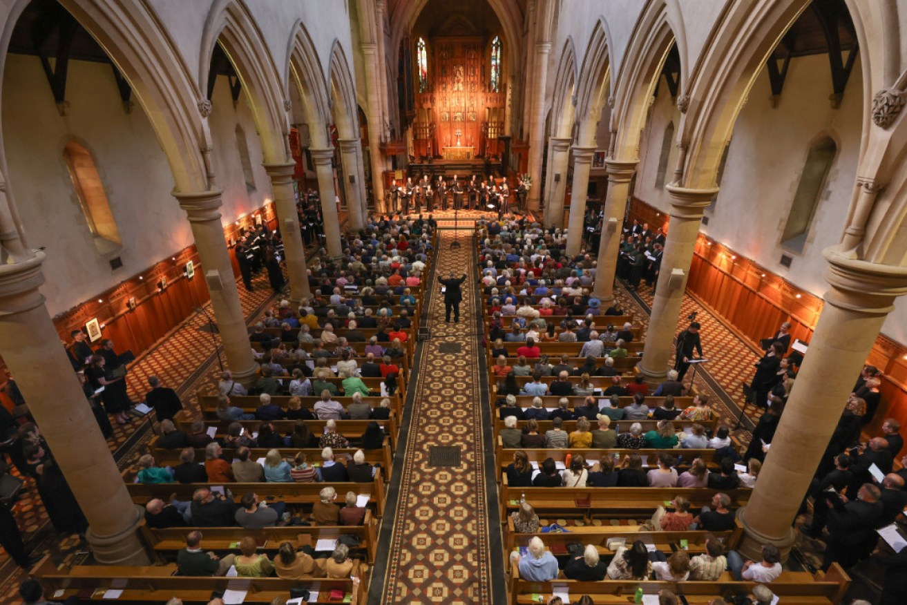 Carl Crossin in the centre aisle of the cathedral, conducting all five choirs in the Adelaide Chamber Choir Festival finale. Photo: Tony Lewis