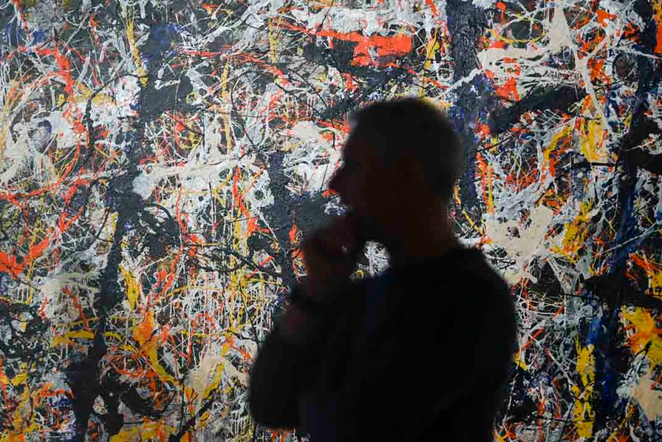 National Gallery of Australia senior paintings conservator David Wise with  'Blue Poles' by Jackson Pollock during conservation work in 2020. Photo: AAP/Lukas Coch