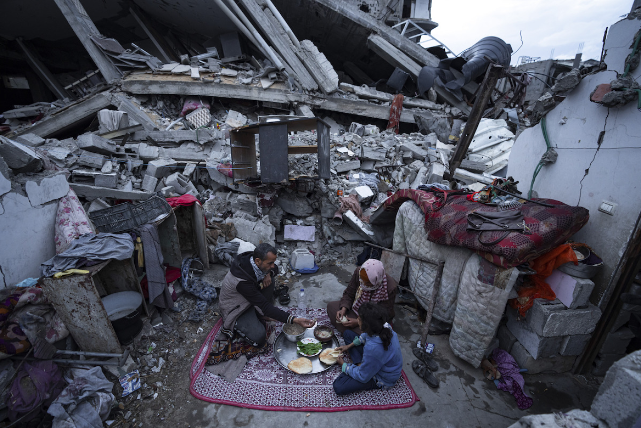 A Palestinian family at their Rafah home which was destroyed by Israeli airstrikes. Photo: AP/Fatima Shbair)